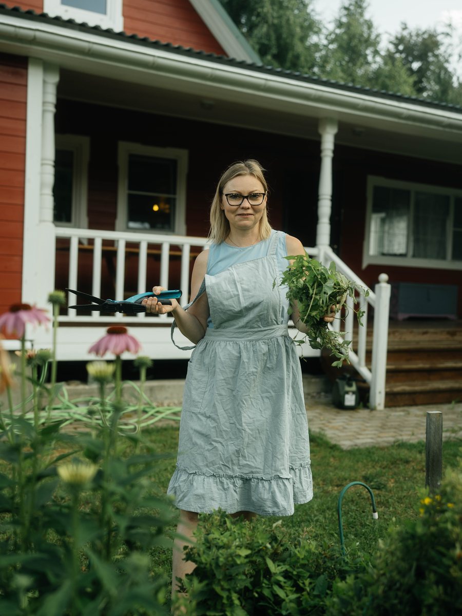 Katya with fresh-cut herbs by the house
